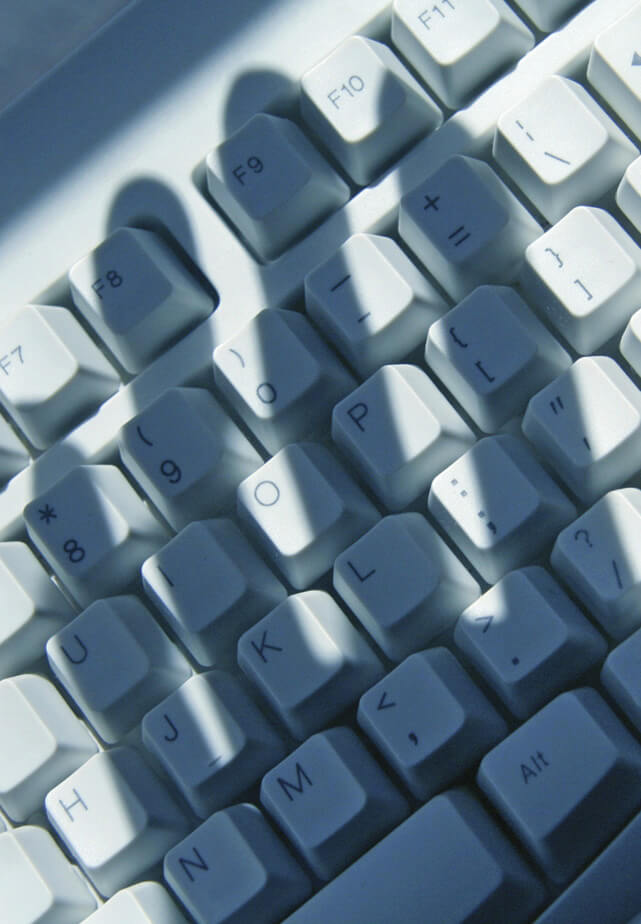 Image of a keyboard with a shadow of a hand hovering over it 