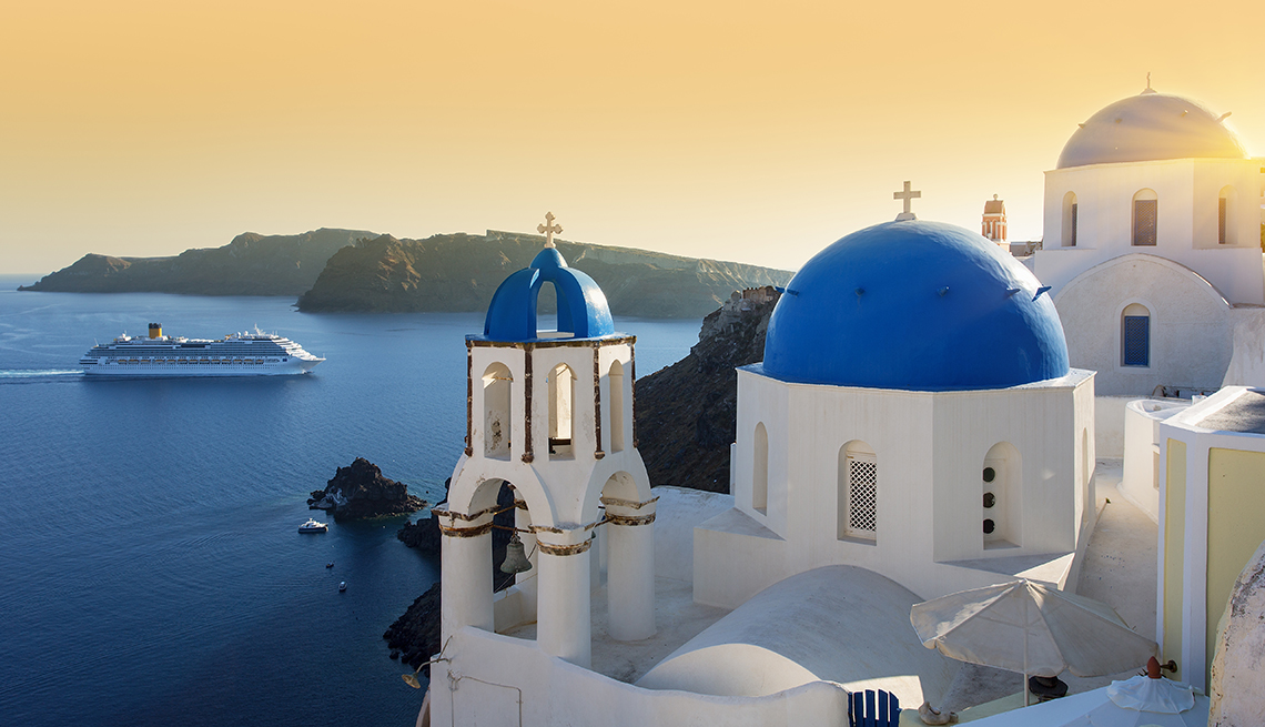 A cruise ship in the distance with a blue-domed church in the foreground