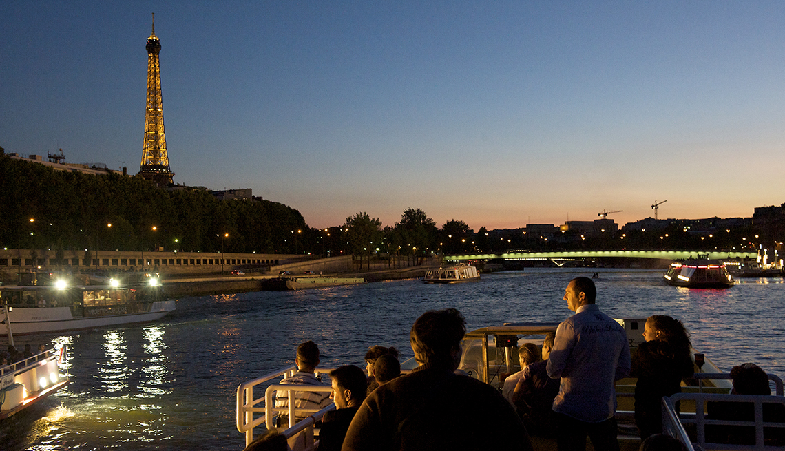 Travelers cruising the Seine River at dusk in summer, view of Eiffel Tower in distance