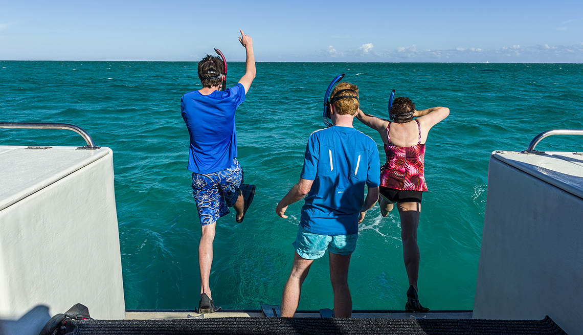 Tourists leap of the rear of a boat with snorkels on