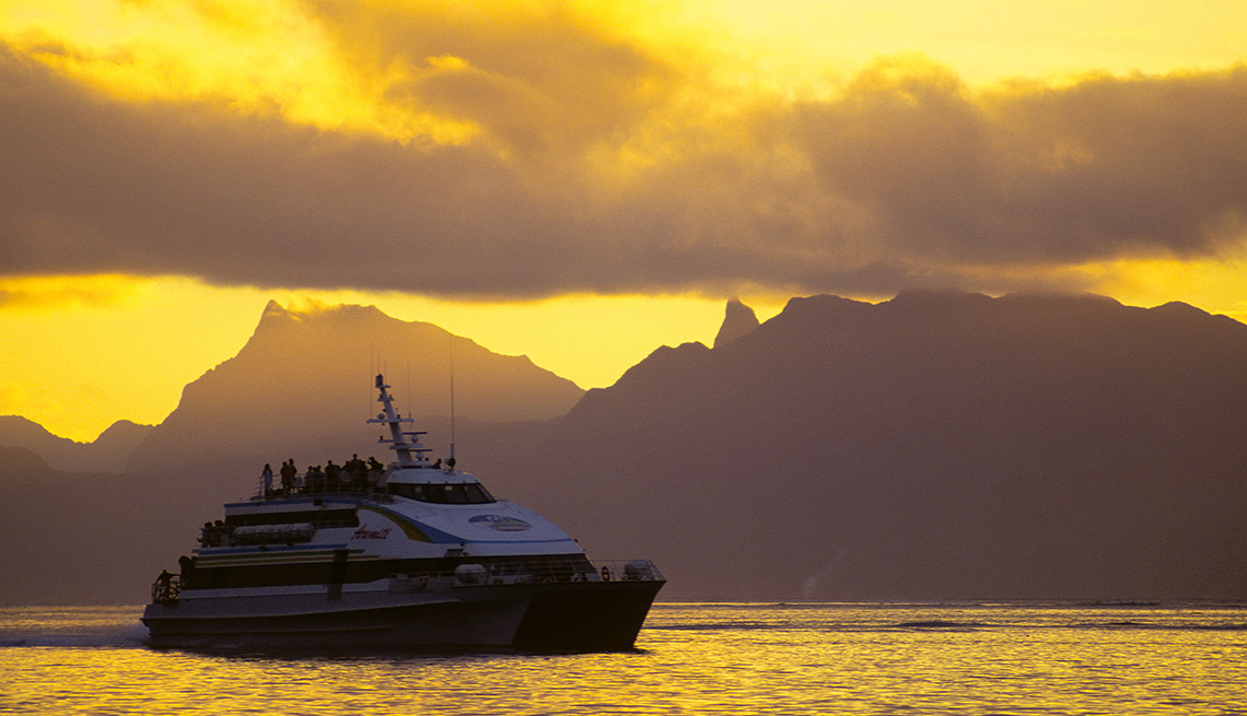 Small cruise ship on water with mountains in the distance