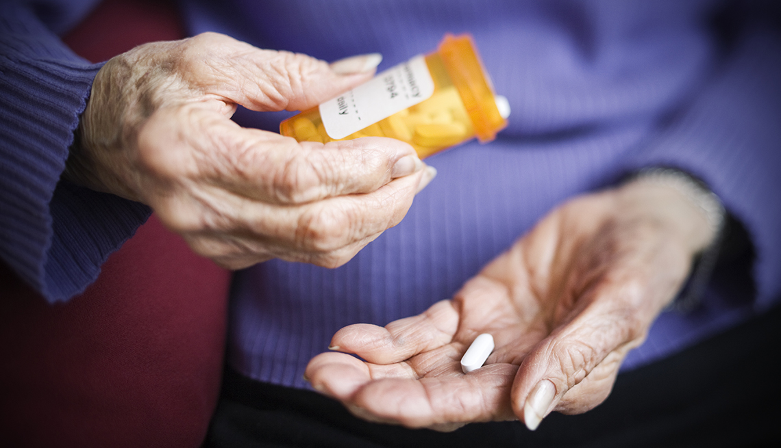 a woman is putting a pill in her hand