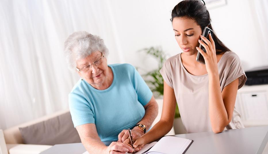 cheerful young woman helping an old person doing paperwork and telephone call