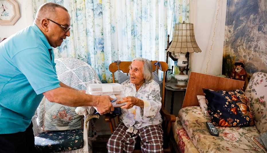 A man delivering a meal to an older woman
