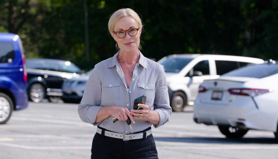 a woman is standing in a parking lot with her phone