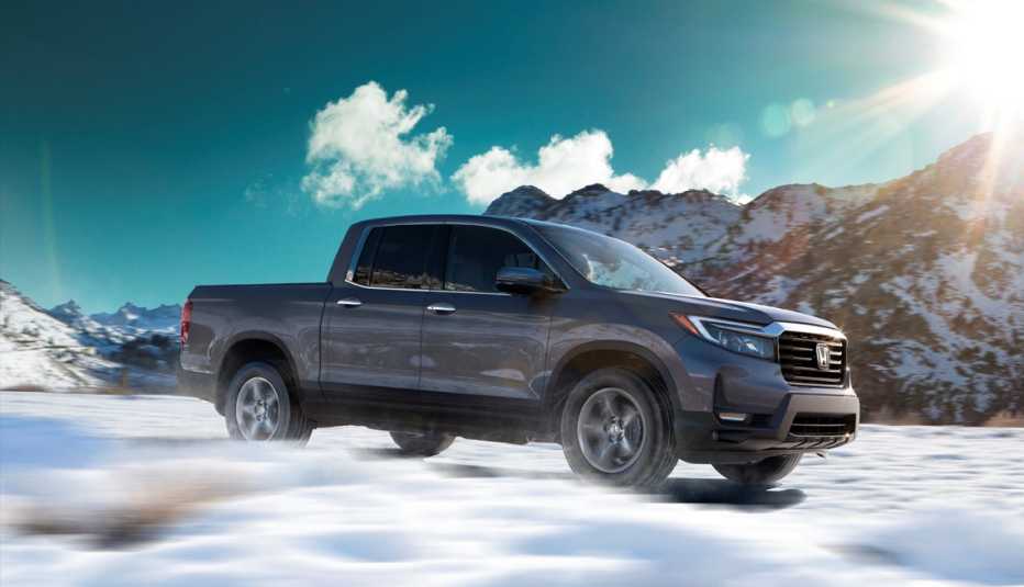 a photo of a twenty twenty two honda ridgeline driving through snowy mountains