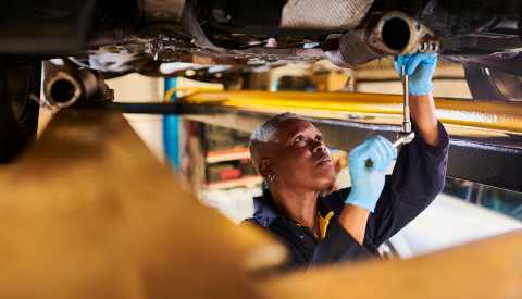 a mechanic looks at the bottom of a car