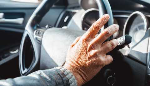 a man's hand rests on a steering wheel