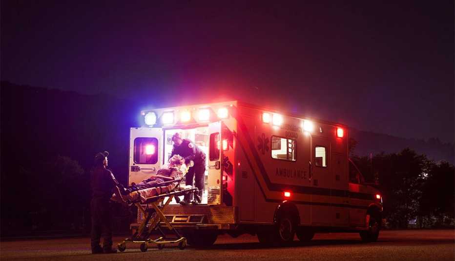 Emergency medical services workers putting putting a patient in an ambulance
