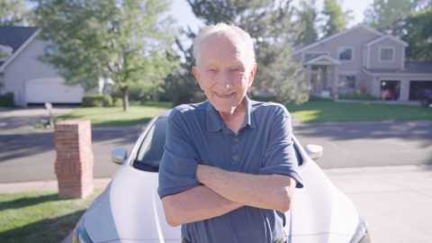 robbie robinson stands in front of a vehicle in a residential neighborhood