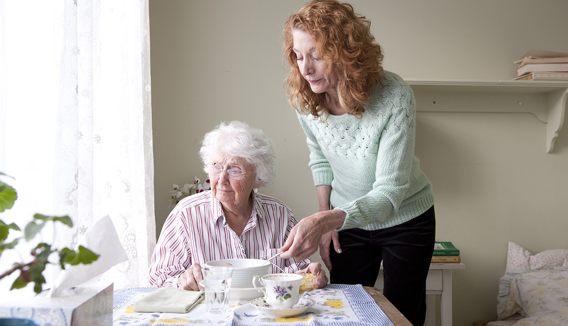 Woman feeding mother at table