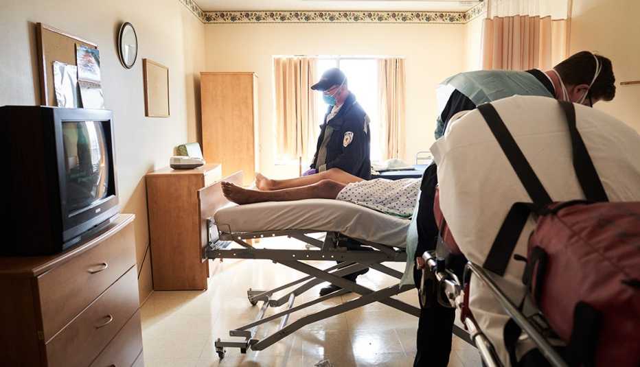 two E M S workers picks up a suspected Covid 19 patient at a nursing home