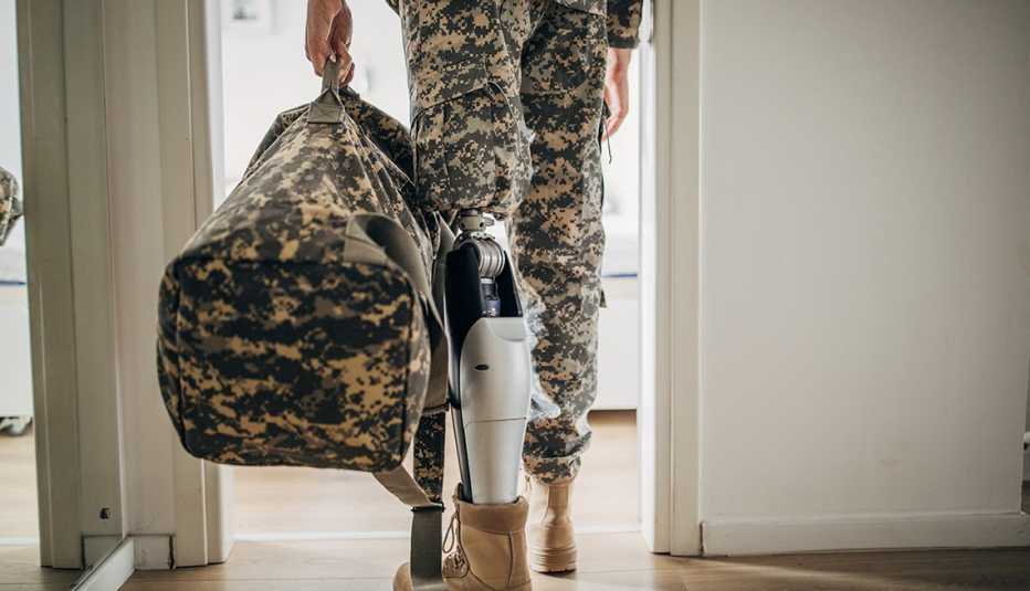 A man in a military uniform with an amputee leg walking through the door of a home