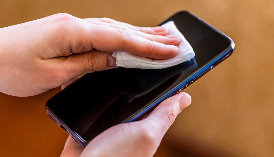 A woman wiping a phone screen with a disinfectant wipe