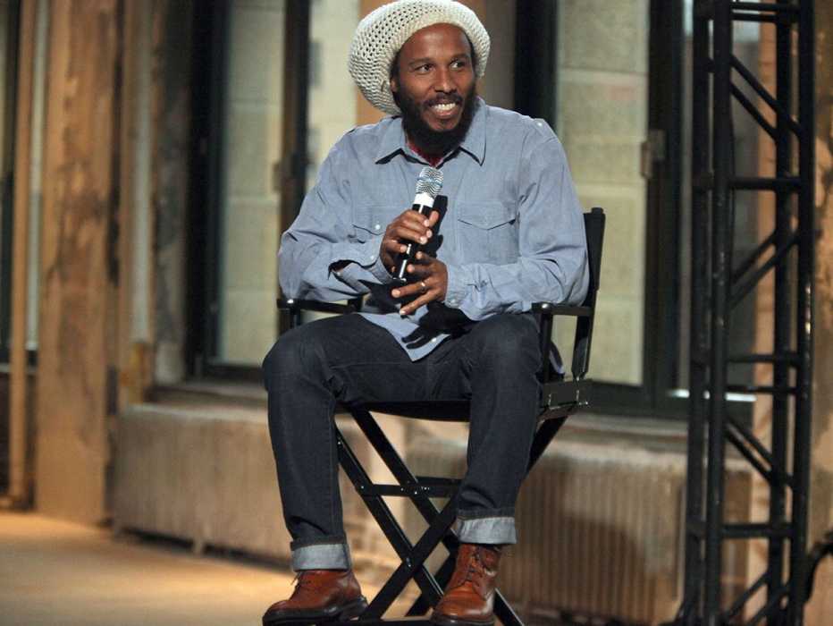 Ziggy Marley in dark denim, light blue dress shirt worn out