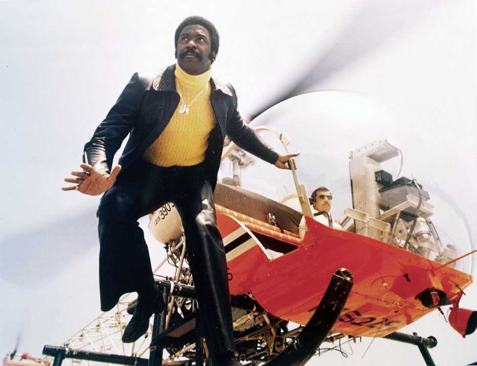 richard roundtree hanging onto a helicopter in a scene from the cbs television series shaft