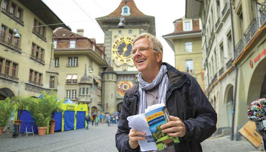 rick steves holding rick steves switzerland guide outside, in between buildings