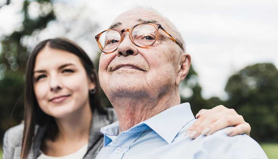 Portrait of self-confident senior man with granddaughter in the background