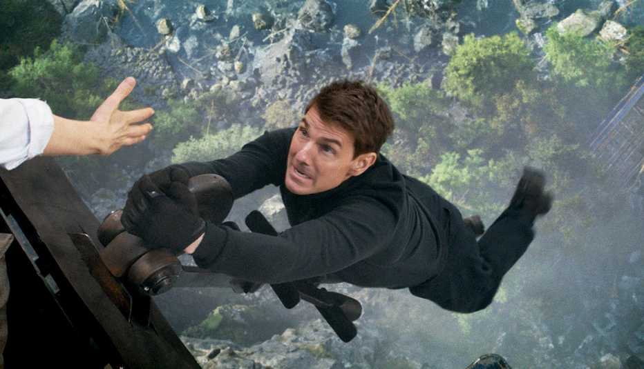 tom cruise hanging from the end of a train car high in the air in the film mission impossible dead reckoning part one
