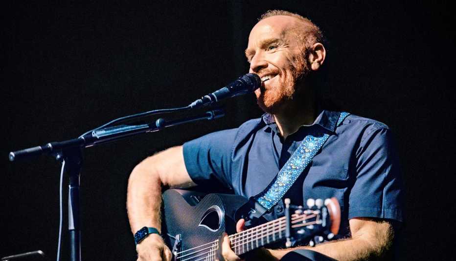 Mike Massé seated with a guitar in front of a microphone