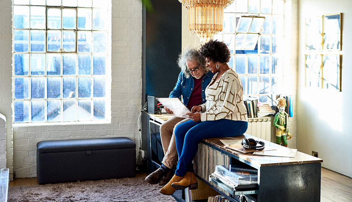 Woman sitting on sideboard, looking at record covers, lifestyle, music, relaxation