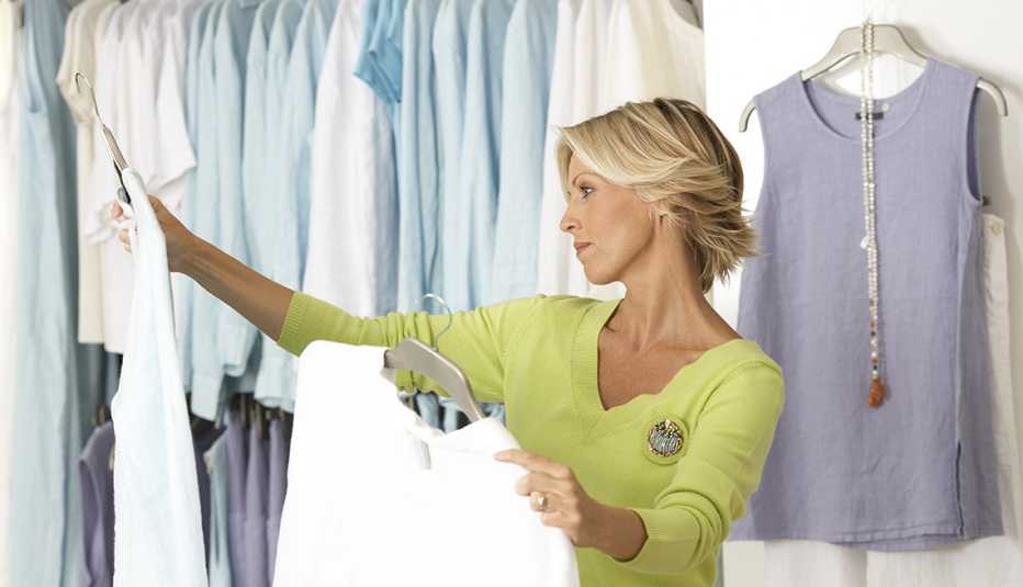 A woman shopping in clothes shop comparing two tops on coathangers