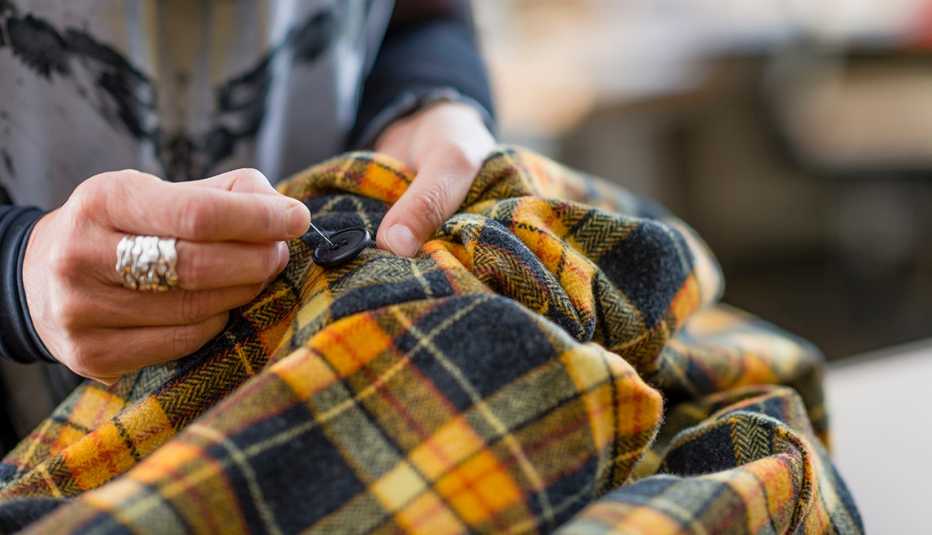 A close up of a woman hand sewing a button onto a jacket