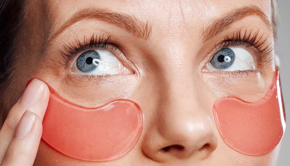 a woman treating herself with under eye patches