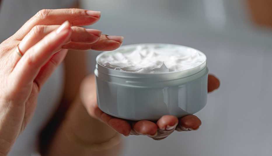 A close up of a woman using moisturizing cream