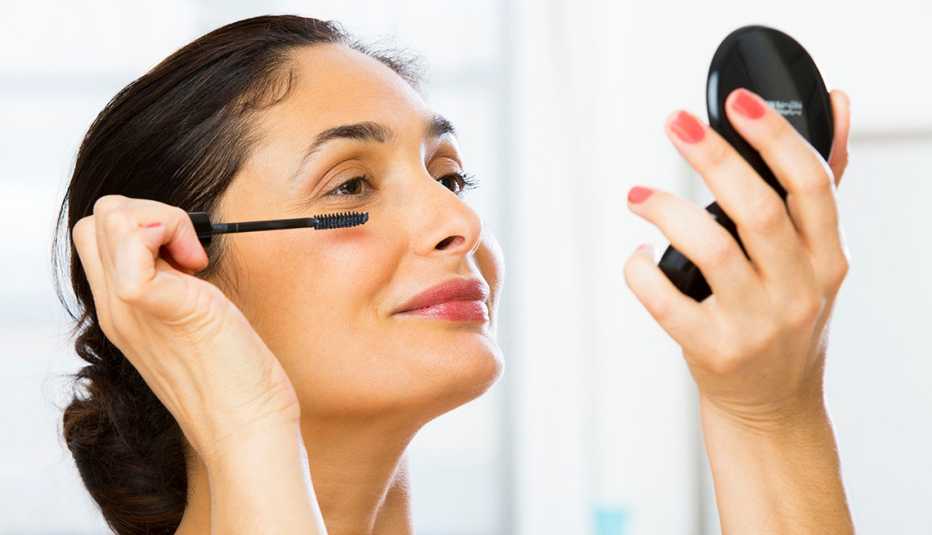 a woman applying makeup on her eyes