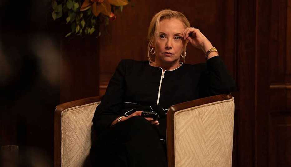 j smith cameron siitting in chair with a smartphone in her hand in a scene from the hbo series succession