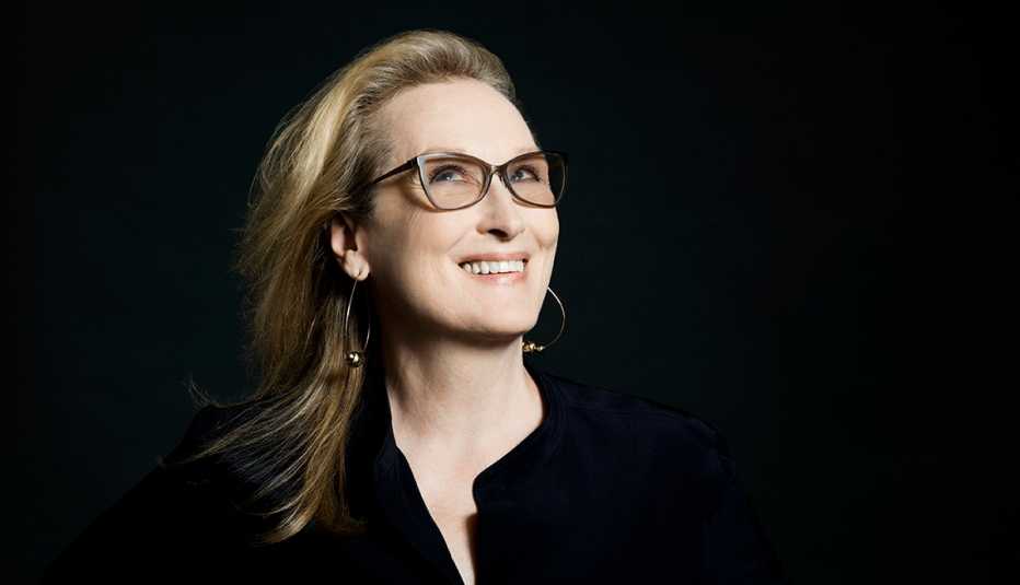 woman with blonde hair and glasses against a black background