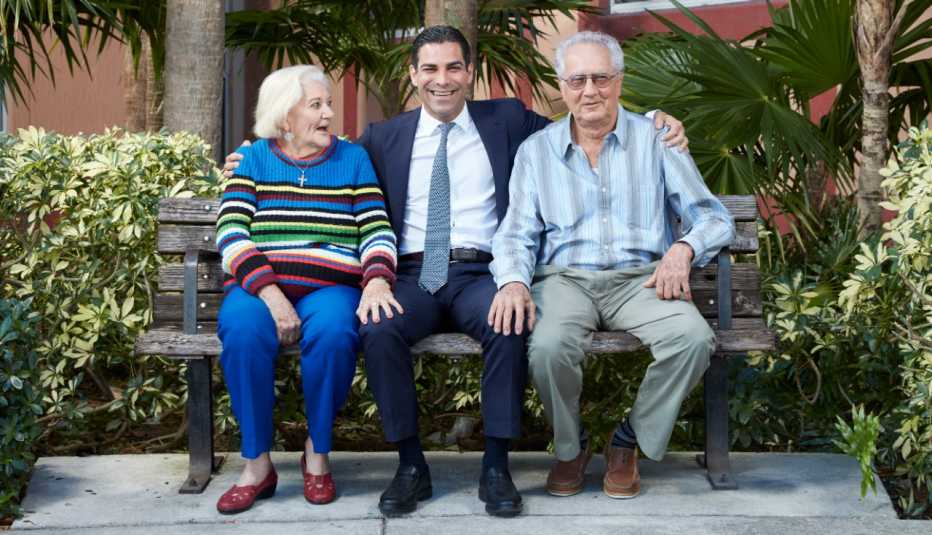 miami florida mayor francis suarez sits on a bench outside an apartment building with two residents