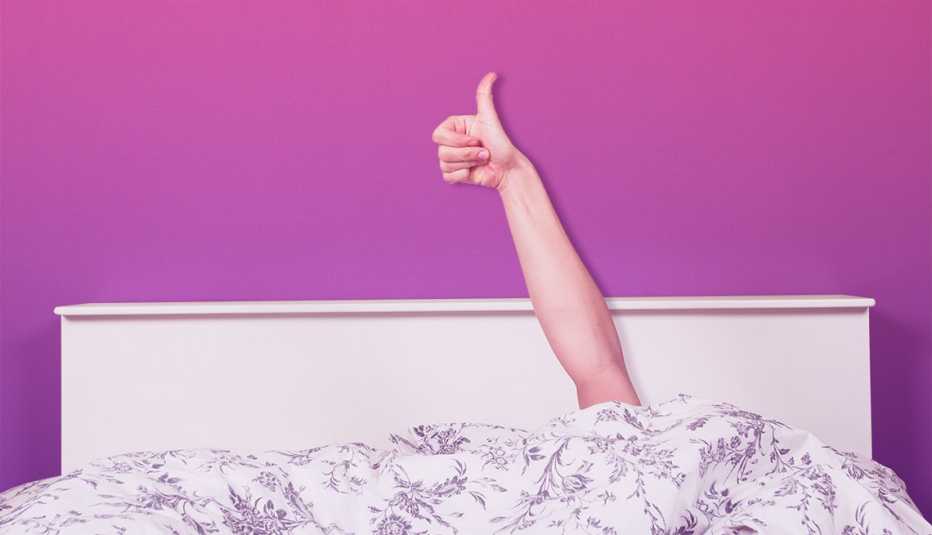 a person in bed giving a thumbs up