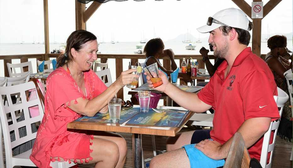 Tracey Minkin and her son, Adrian Stone, toast with drinks in a beachfront cafe in Sainte-Anne, Martinique.