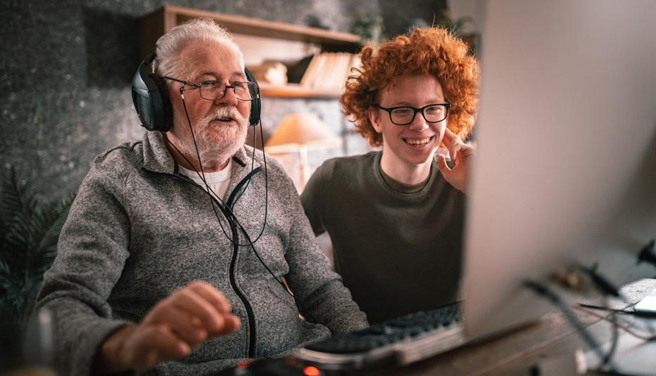 grandfather and grandson sitting around table at home and using computer