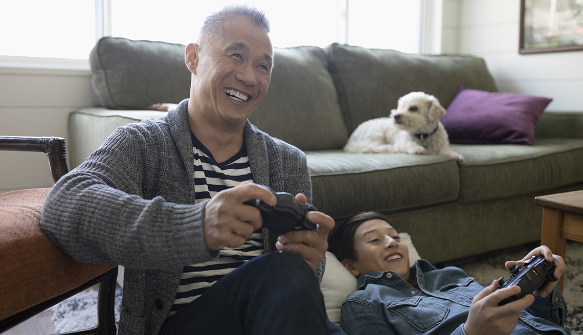 father and son playing video games at home on the couch