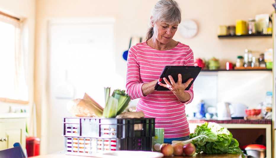 A woman looking at a tablet with food on a table