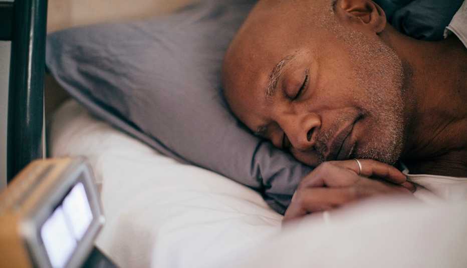 man asleep in bed showing alarm clock on bedside table