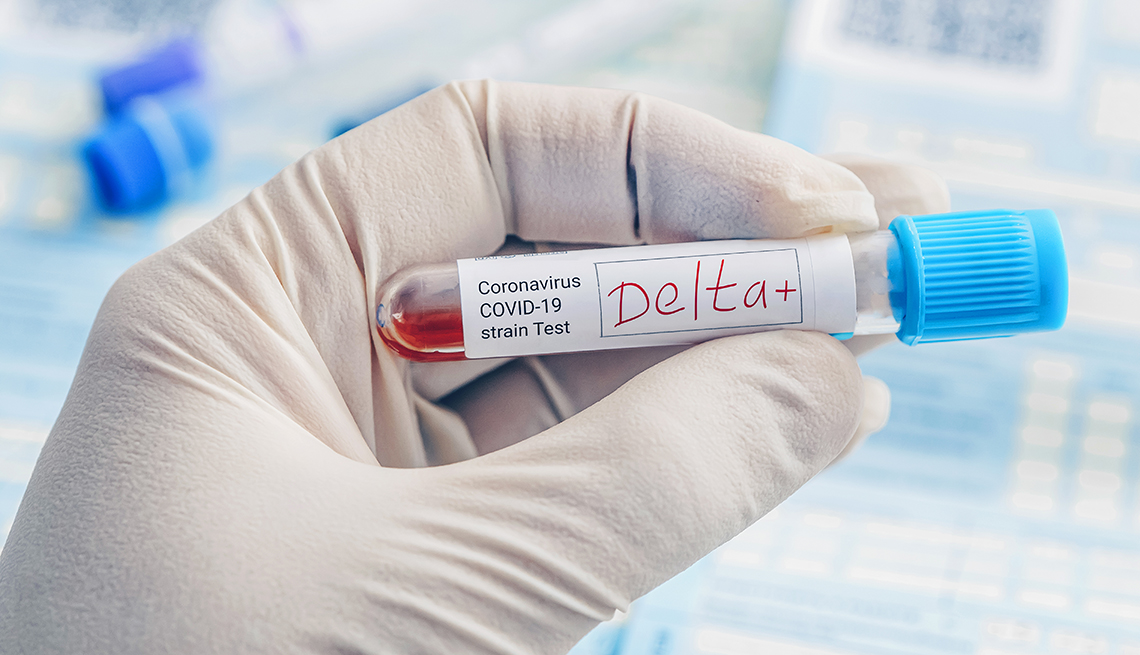 gloved hand holding a vial with a COVID-19 strain test sample shows the word Delta+