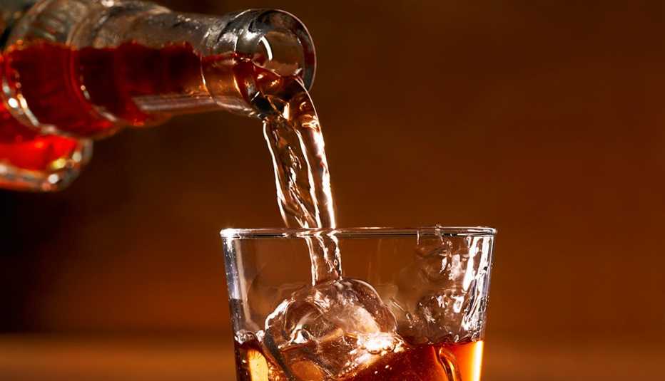 whisky being poured from a bottle into a glass with ice