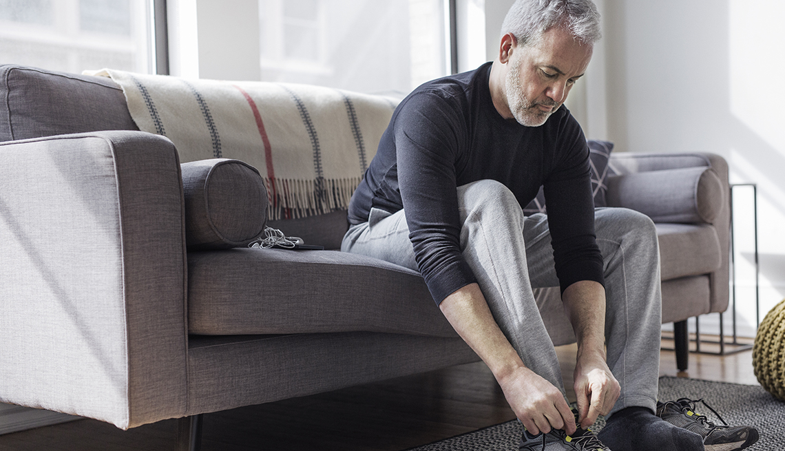 Man sits on couch and ties his sneaker