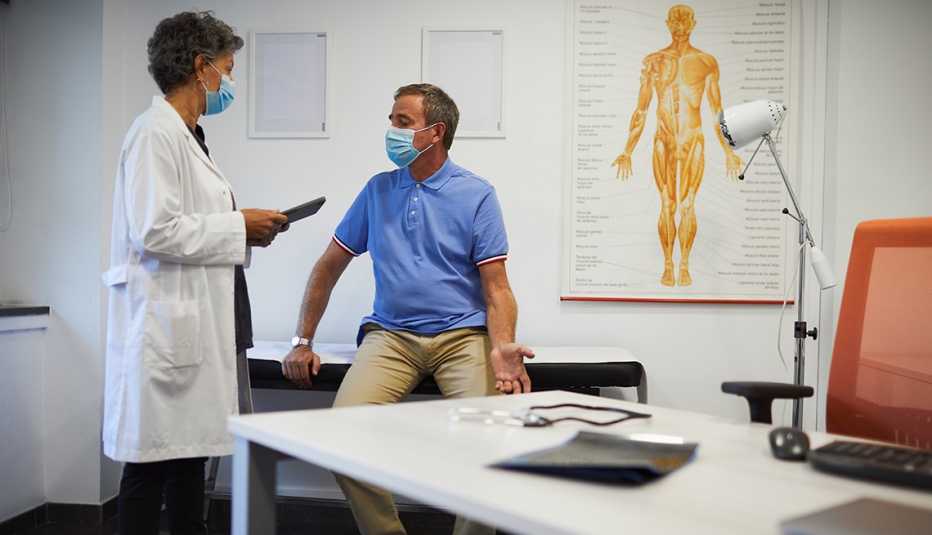 Patient talking to his doctor. Both wearing face masks.