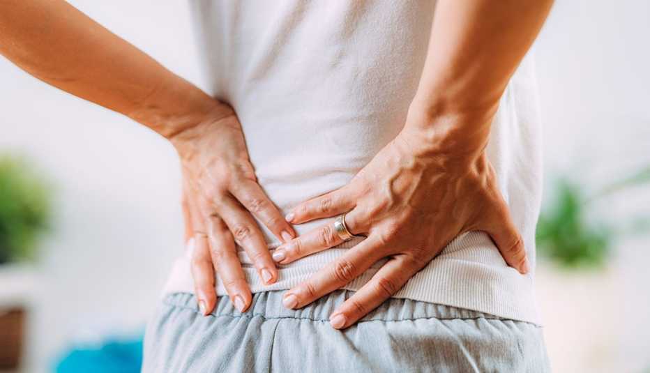 woman grabs her lower back in pain