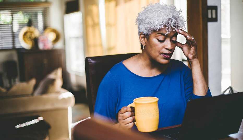 woman with a headache working at laptop on table at home