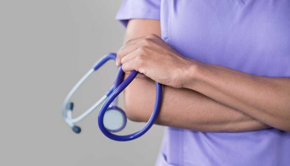 Female nurse holding stethoscope, arms folded.