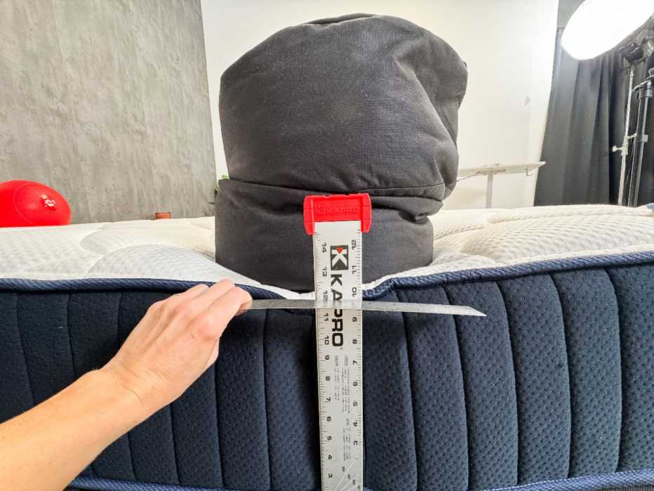 The edge of the DreamCloud Classic Hybrid mattress being tested with a sandbag