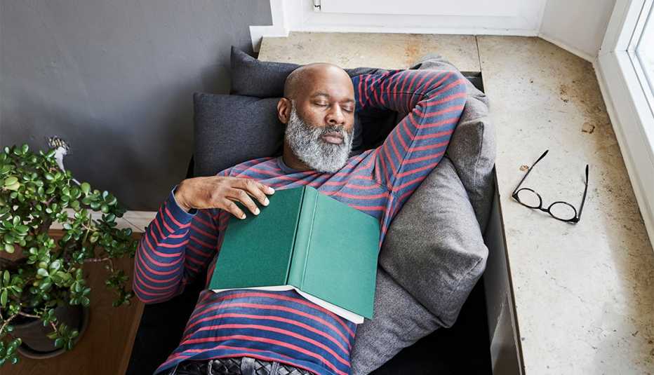 man taking a nap on a couch near a window