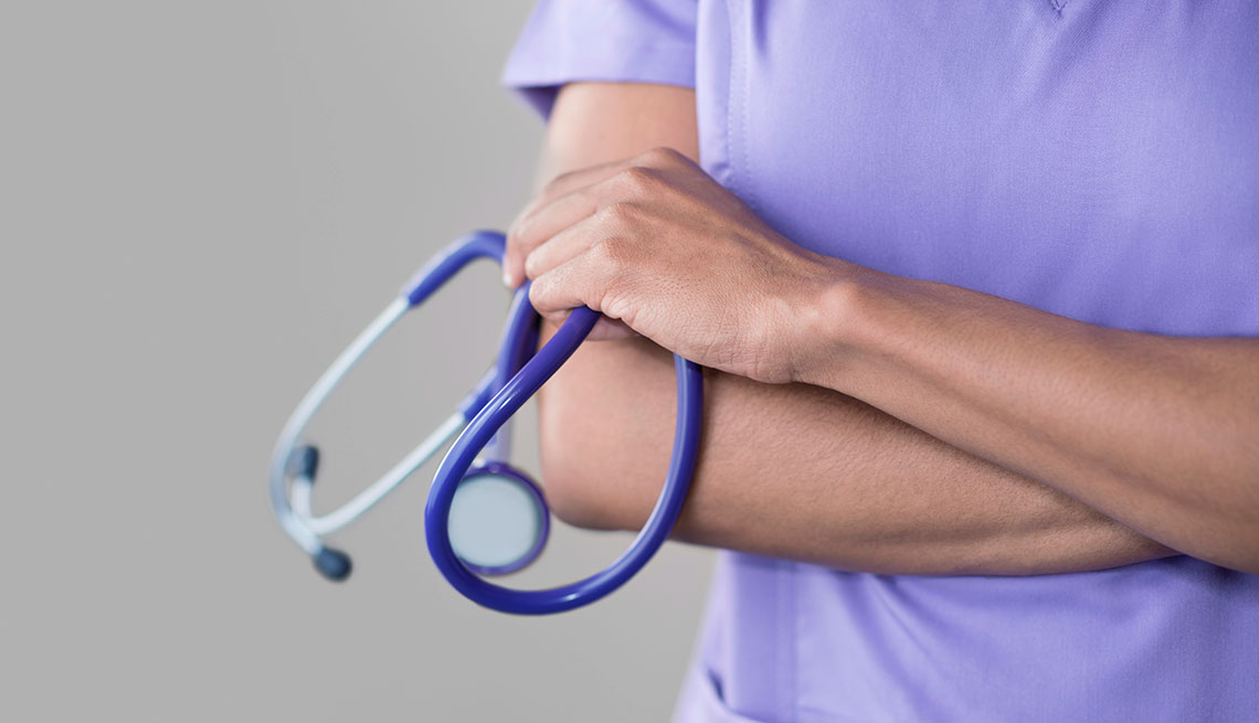 Female nurse holding stethoscope, arms folded.