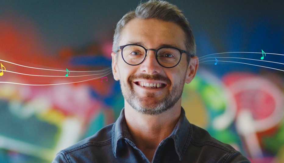 a man with glasses smiling with music notes behind him